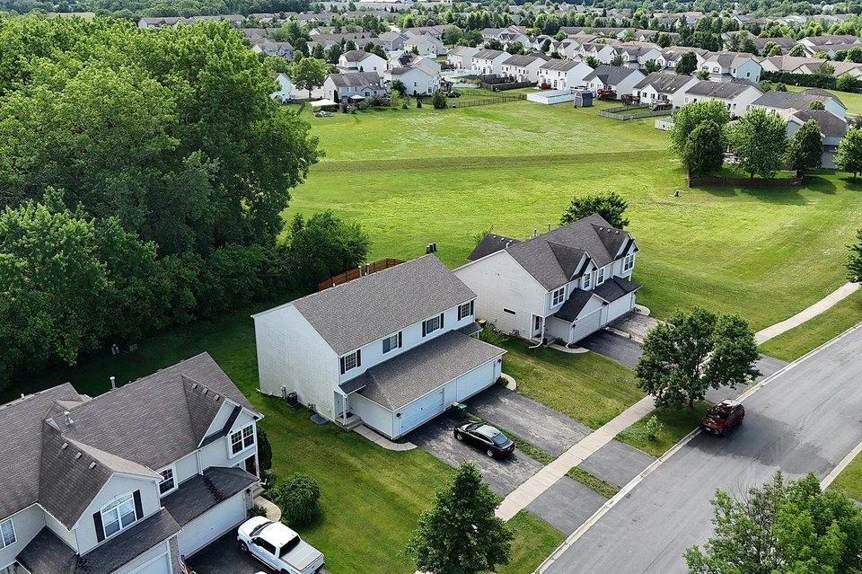 Aerial view of suburban neighborhood with houses, green lawns, and trees.