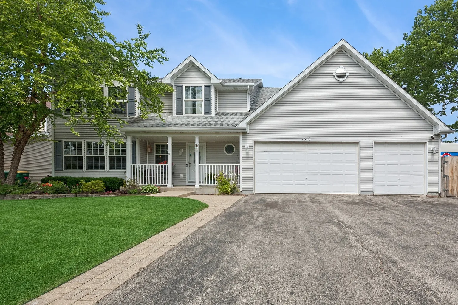Modern two-story house with gray exterior, two-car garage, and landscaped yard.