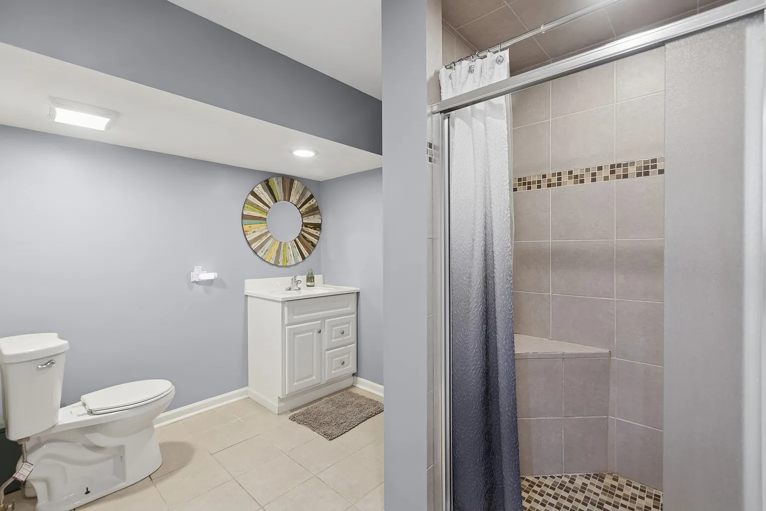 Modern bathroom with toilet, white vanity, round mirror, and glass shower.