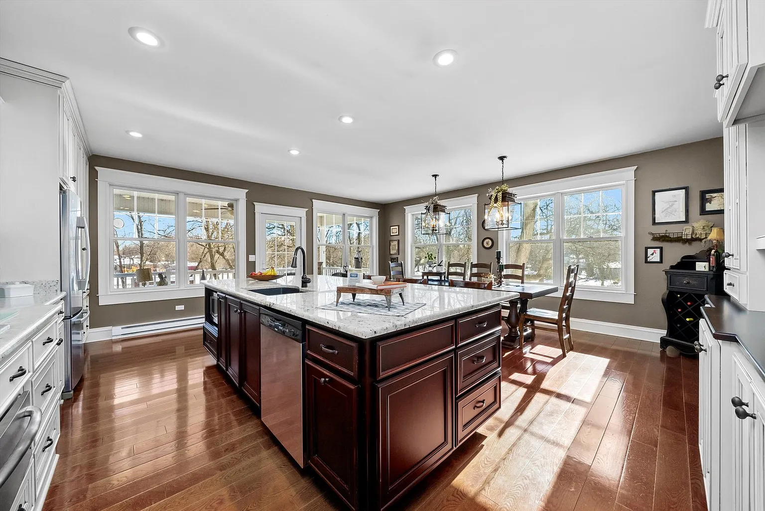 Spacious kitchen with marble island, dark wood cabinets, hardwood floors, and natural light.