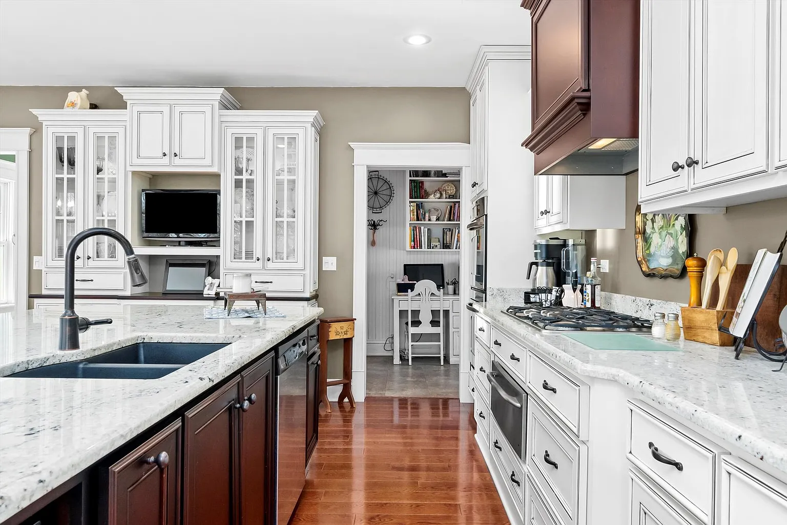 Modern kitchen with granite countertops, gas stove, stainless appliances, and large windows.