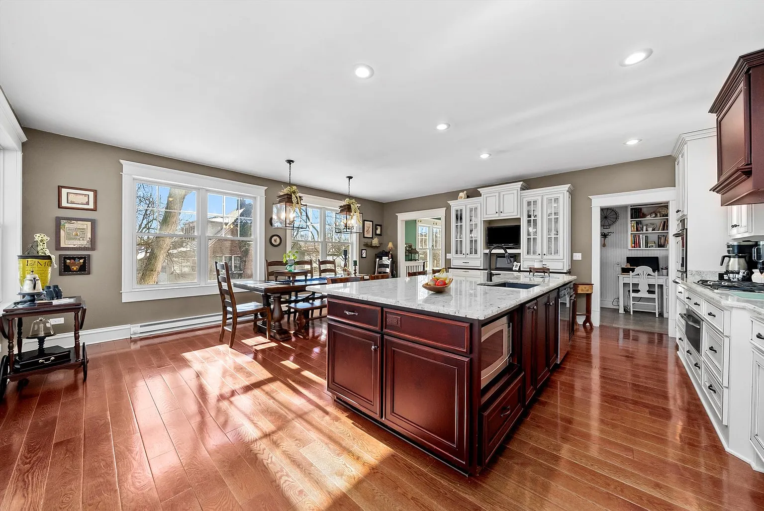 Modern kitchen with white and dark wood cabinets, island sink, granite countertops, and stainless appliances.