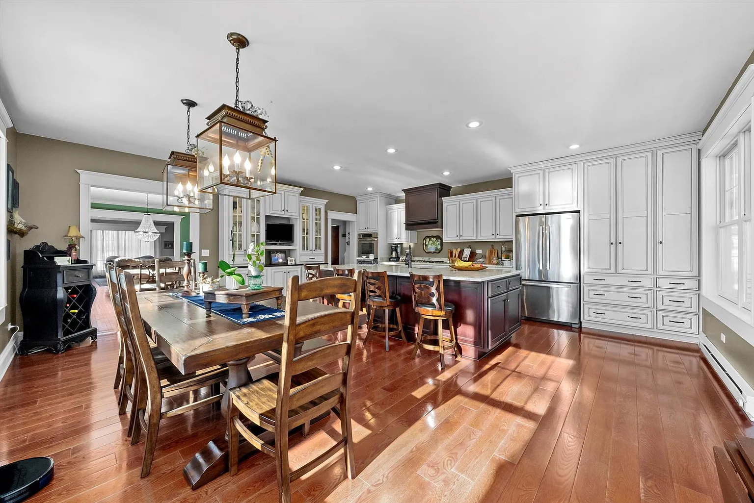Modern kitchen with white and dark wood cabinets, island seating, stainless appliances, and hardwood floors.