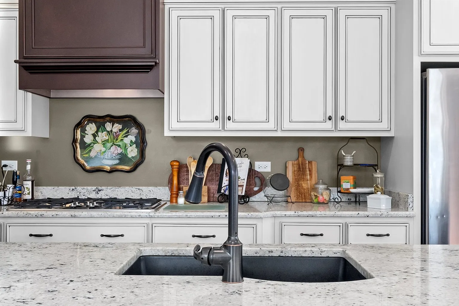 Modern kitchen with white cabinets, granite countertop, undermount sink, and dark faucet.