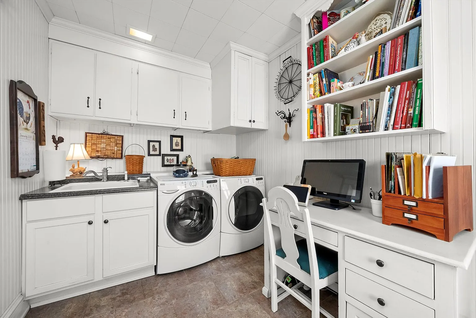 Laundry room with washer, dryer, cabinets, sink, and small workspace.