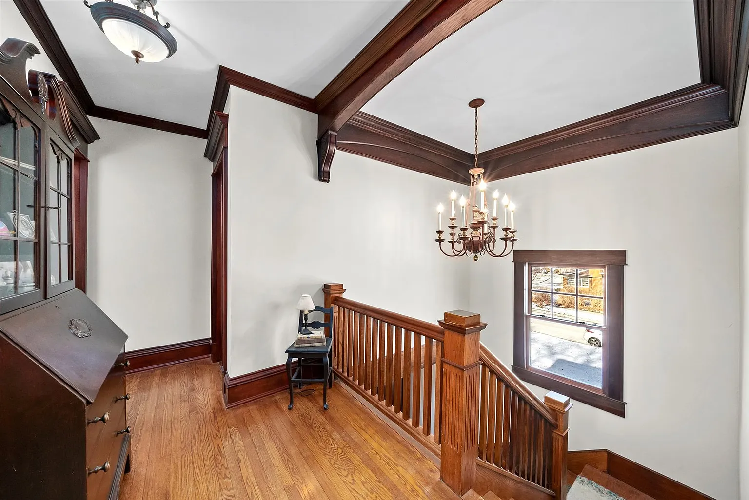 Staircase with wooden railings, chandelier, and light walls with dark wood trim.
