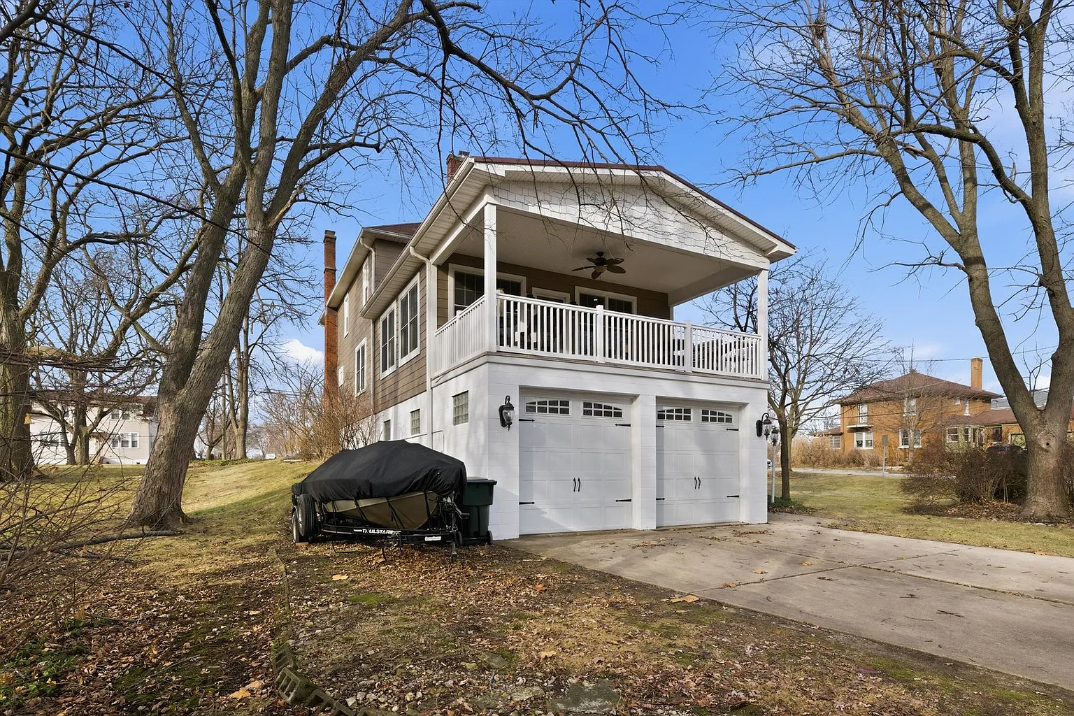 Two-story white house with garage, balcony, and suburban setting.