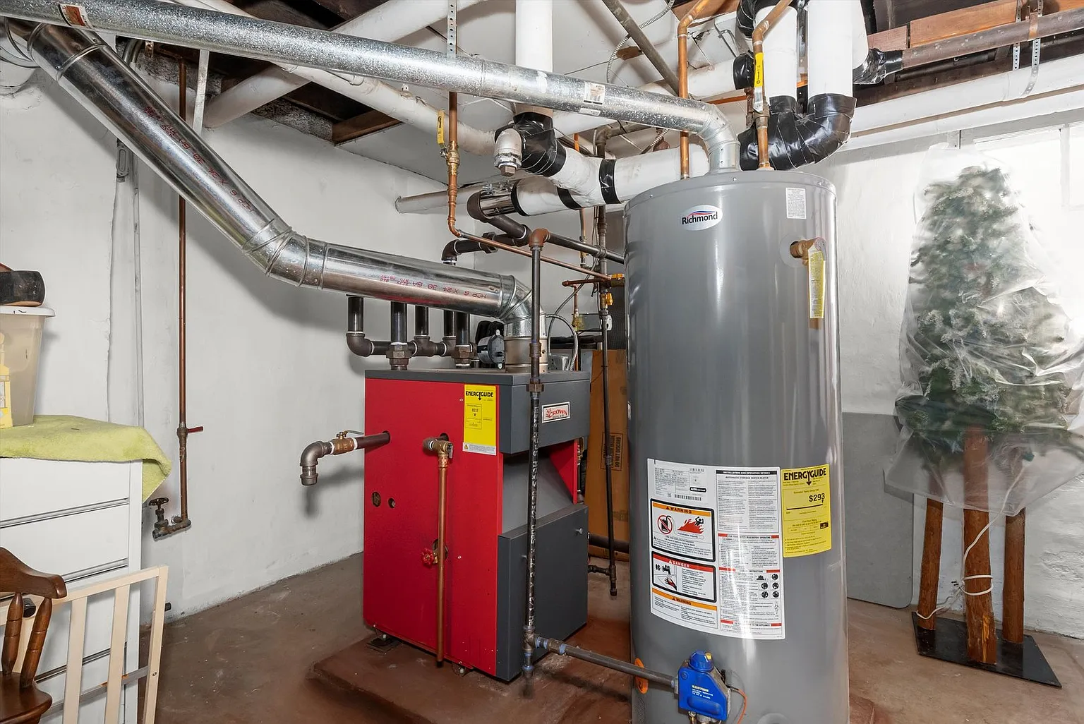 Basement with furnace, water heater, and exposed pipes.