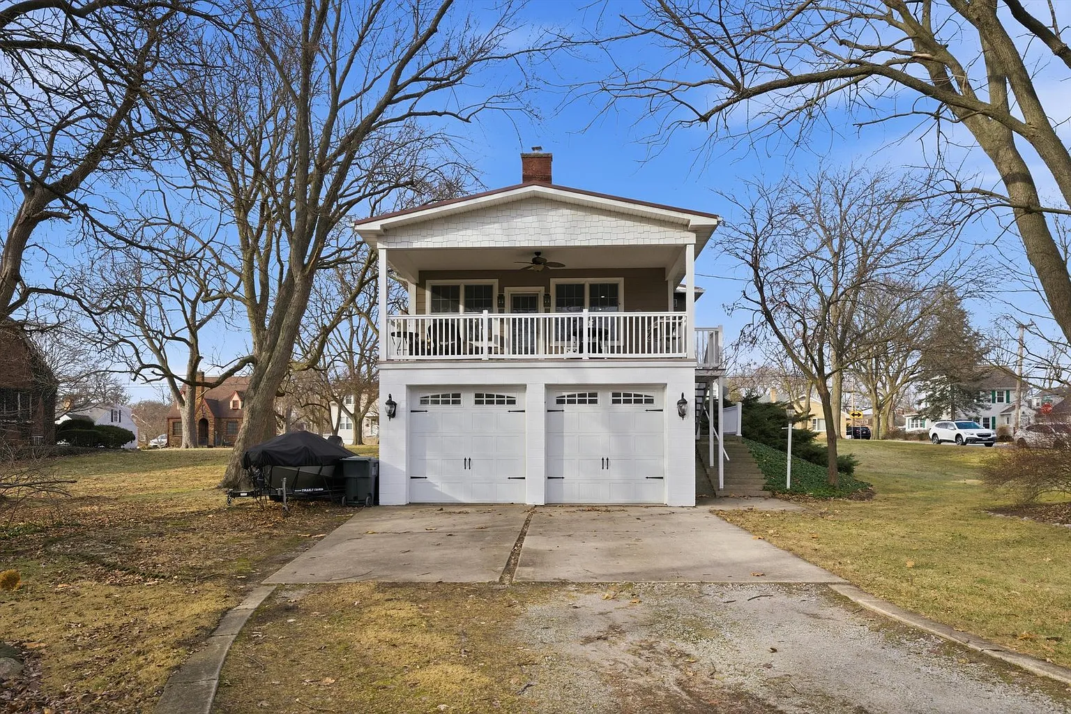 Two-story white house with garage, balcony, and suburban setting.