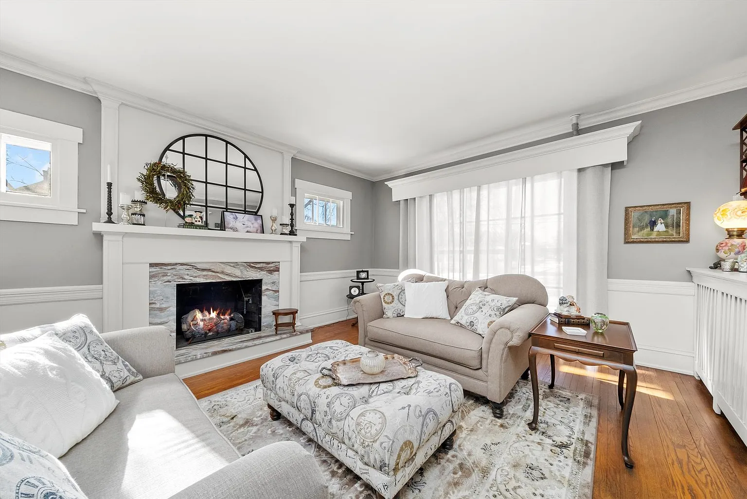 Cozy living room with gray walls, white sofa, ottoman, armchair, and fireplace.