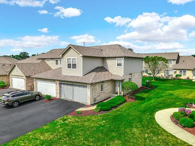 Aerial view of two-story house with landscaped yard, driveway, and nearby home