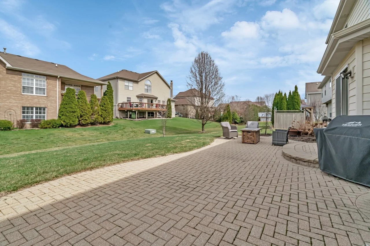 Backyard with paved patio, green lawn, and nearby houses.