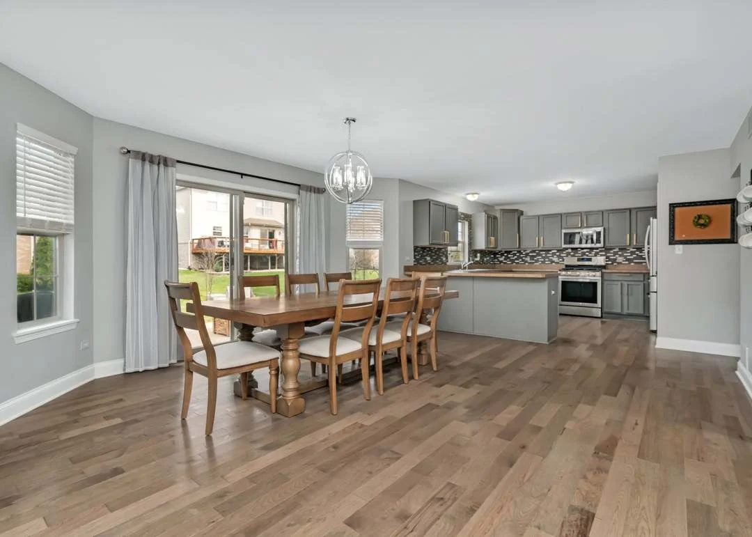 Spacious kitchen and dining area with wood floors, gray cabinets, and stainless steel appliances.